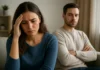 Why Your “Perfect” Man May Be Quietly Draining Your Soul Woman resting her forehead against her hand while a man sits behind her with folded arms.