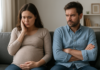 Pregnancy Reveals a Different Marriage | Bella Kent Pregnant woman holding her abdomen while a man sits beside her with folded arms.