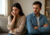 Is Relationship Drift Normal or a Sign of Breaking? Two adults sitting with folded arms and serious expressions on a sofa.