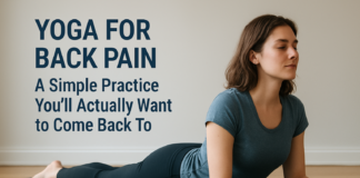 Yoga for Back Pain: A Simple Practice You’ll Actually Want to Come Back To Woman practicing a gentle Sphinx yoga pose on a mat in a bright room for back pain relief