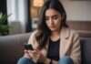 Dating App Burnout: The Part Nobody Explains Until You’re Already in It Woman looking down at her phone while sitting on a sofa.