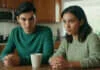 Financial Generosity & Power Dynamics in Young Couples Two young adults talking at a kitchen table beside a plain mug.