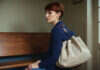 Long-Distance Relationship Doubts Before an Expensive Visit A woman with short auburn hair and a plain travel bag waiting on a bench.