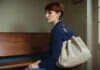 Long-Distance Relationship Doubts Before an Expensive Visit A woman with short auburn hair and a plain travel bag waiting on a bench.