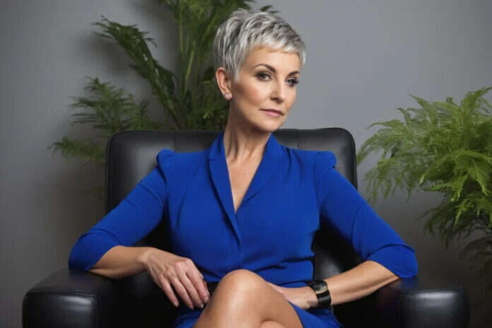 Woman with short gray hair sitting in an armchair in a bright office.
