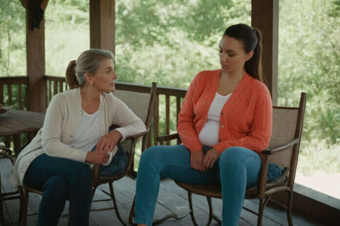 Two women of different ages talking together on a porch.