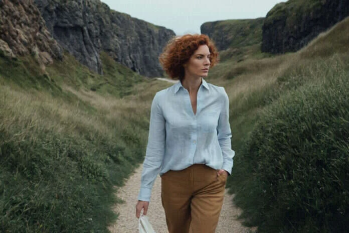 A woman taking a quiet walk through a grassy coastal valley.