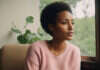 15 Red Flags Draining Your Feminine Energy Woman in a pink blouse beside greenery.