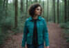 How I Healed After Loving a Man Who Couldn’t Love Me Back A woman with short curls and a teal jacket walking through woods.