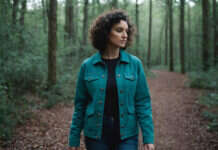 How I Healed After Loving a Man Who Couldn’t Love Me Back A woman with short curls and a teal jacket walking through woods.