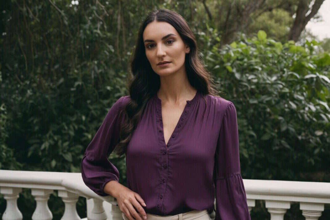 A woman in a purple blouse pausing on a garden terrace.