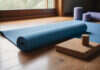 Yoga for Back Pain: Gentle Routines That Help A rolled yoga mat, plain cork blocks and a bolster beside a window.