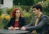 Black Cat Girlfriend Golden Retriever Boyfriend: What It Means A woman with red curls and a man with dark curls talking at a garden table.