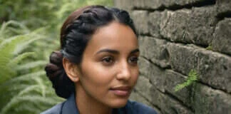 Anxiety and Perfectionism: What Can Help When Your Brain Won’t Stop Scanning for Problems A woman pausing beside a stone wall and ferns.